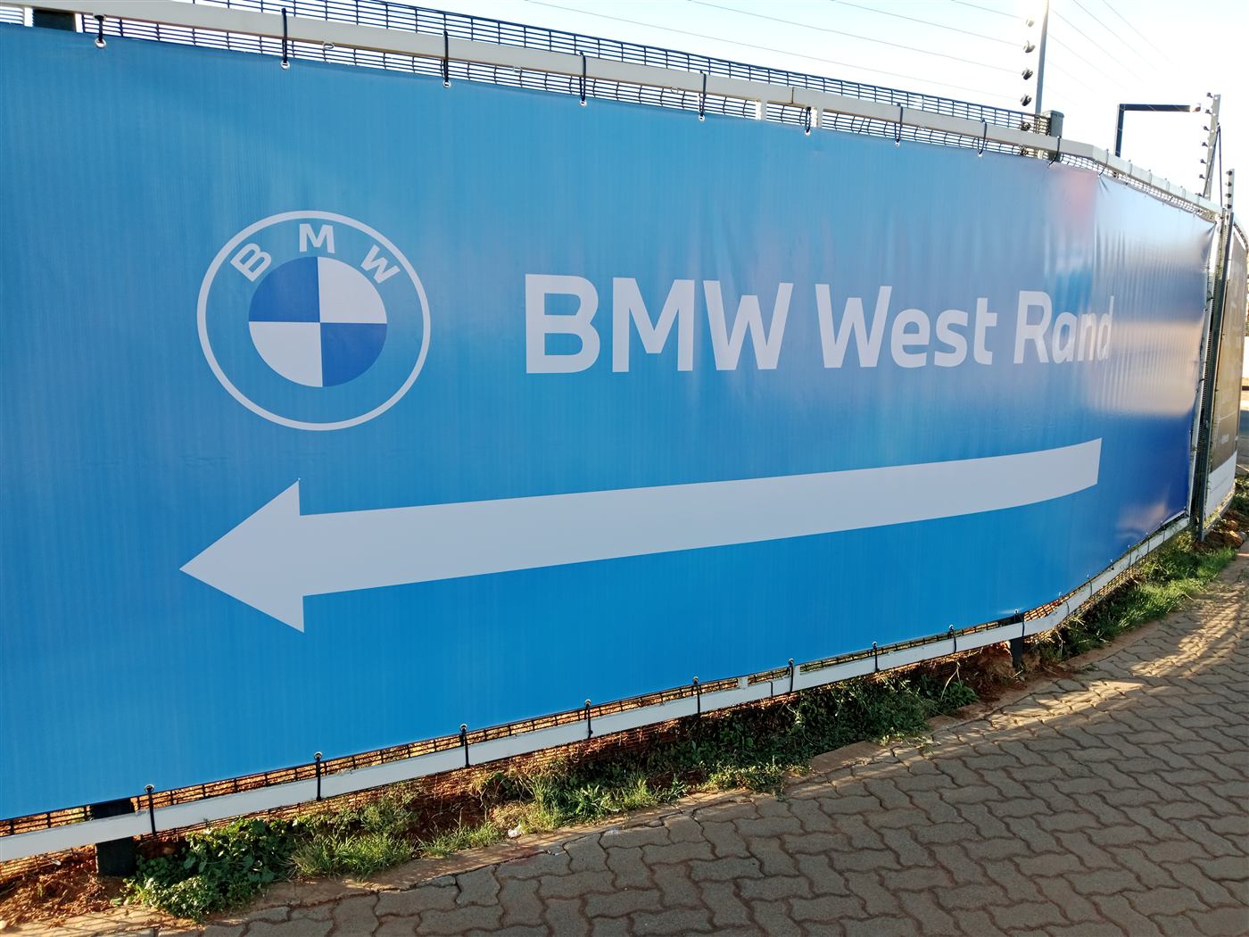 BMW West Rand branded fence hoarding wrap with directional arrow
