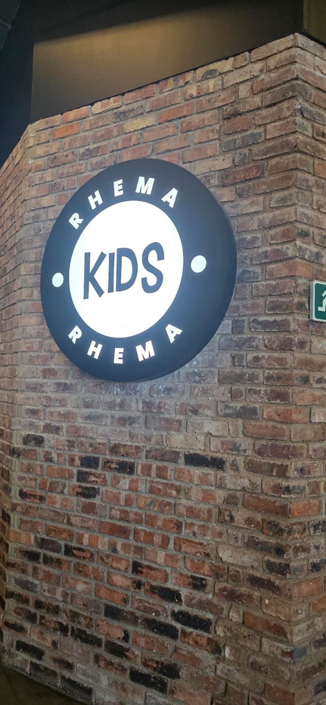 Rhema Kids illuminated circular lightbox sign on a brick corner